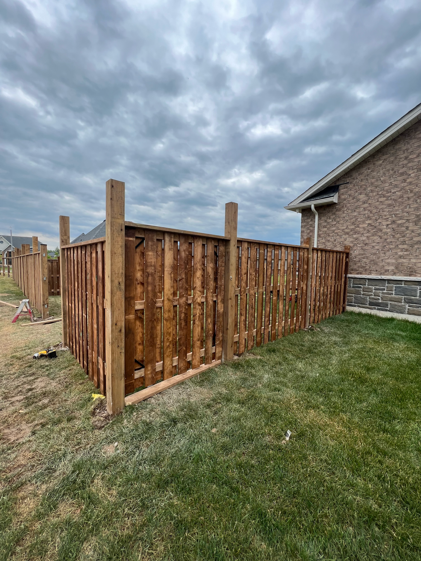 A wooden fence is being built in the backyard of a house.