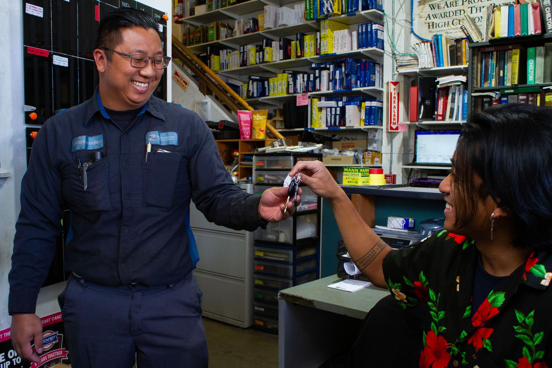 Smiling man in work uniform handing keys to smiling woman. | Dana Meyer Auto Care