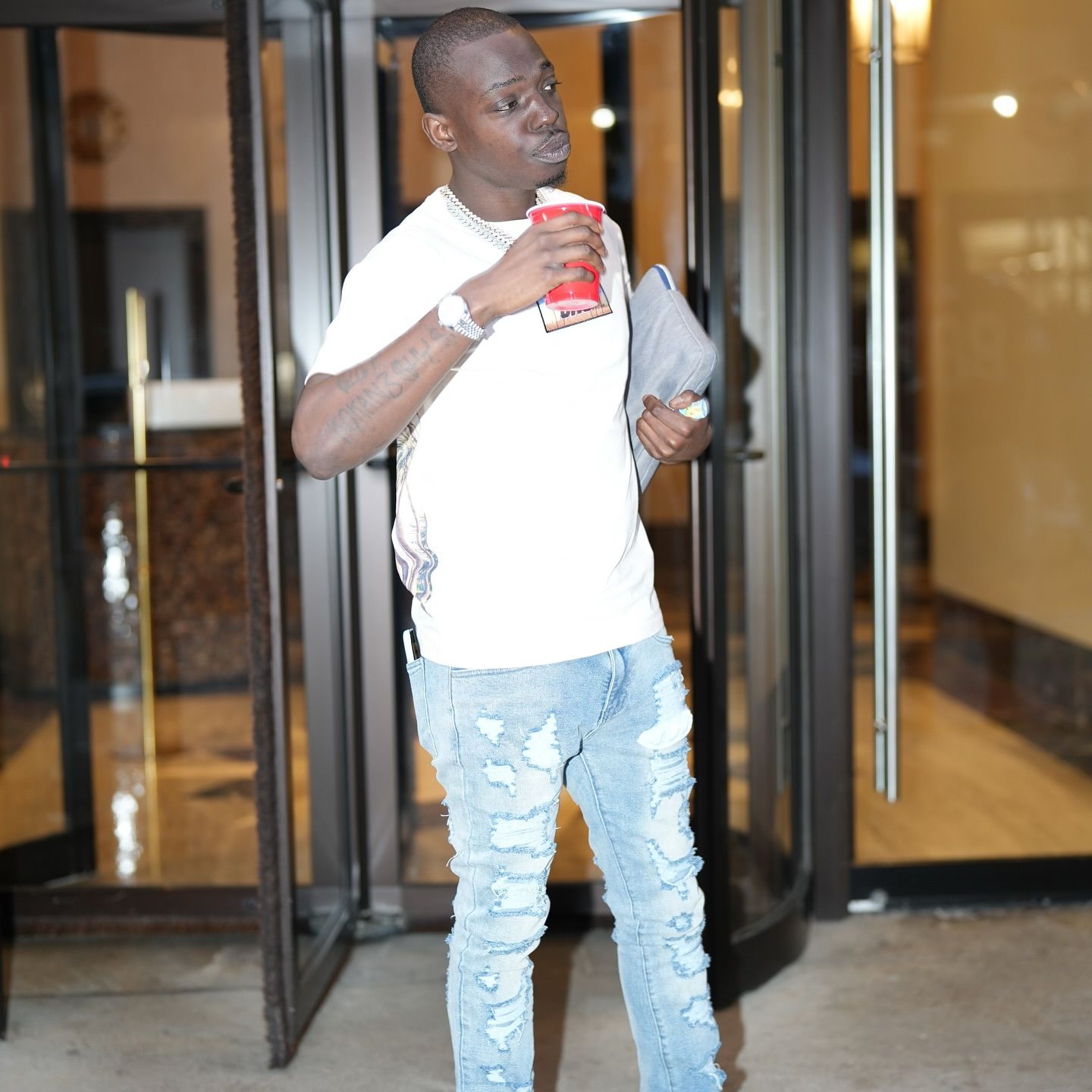 A man standing in front of a door holding a can of soda