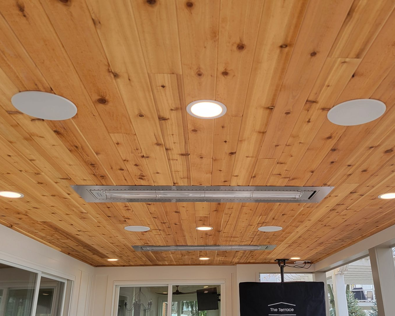 Wooden ceiling with recessed lights and speakers, outdoor patio.