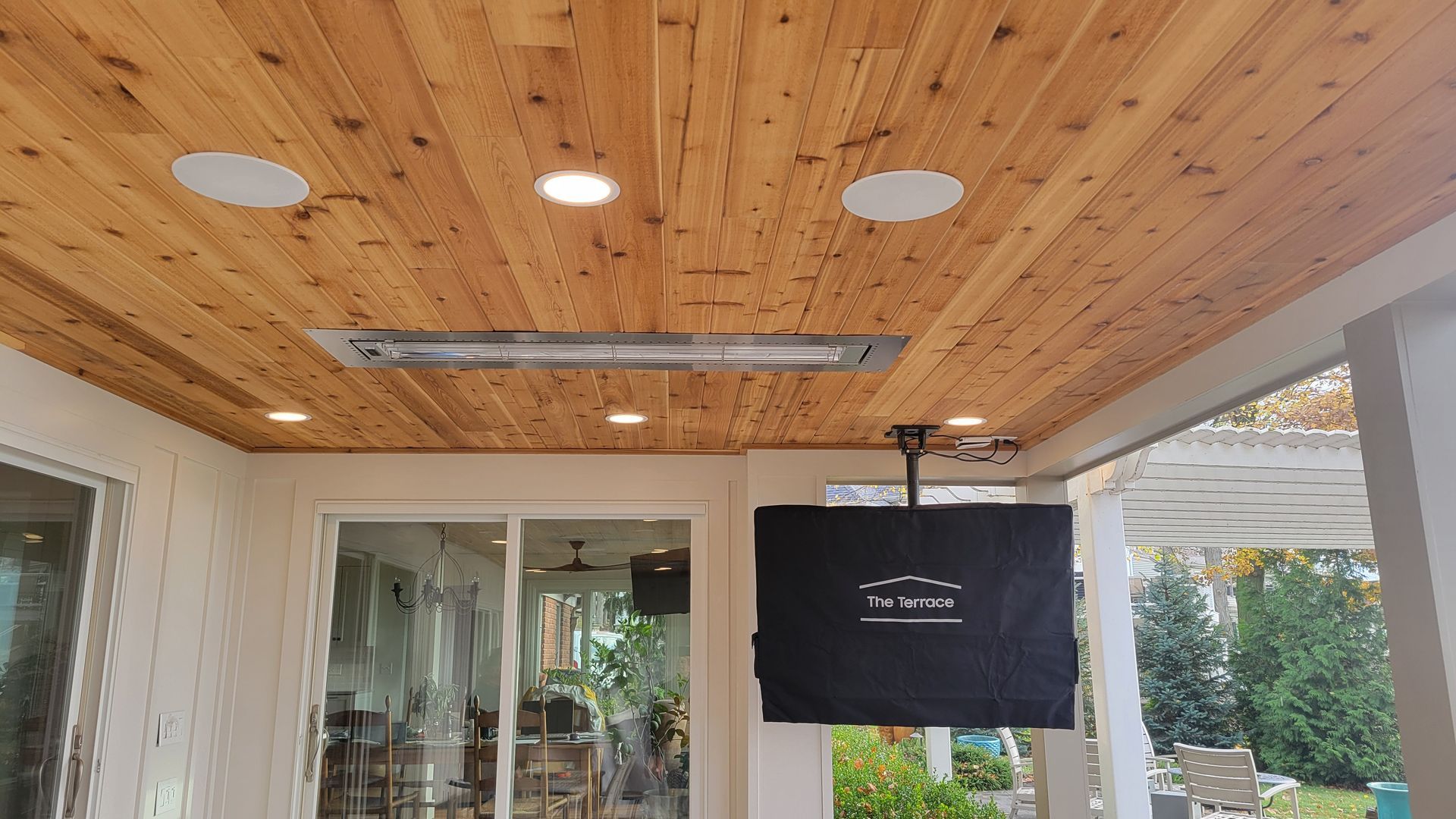 Outdoor patio with wooden ceiling, recessed lighting, heater, speakers, and covered TV.