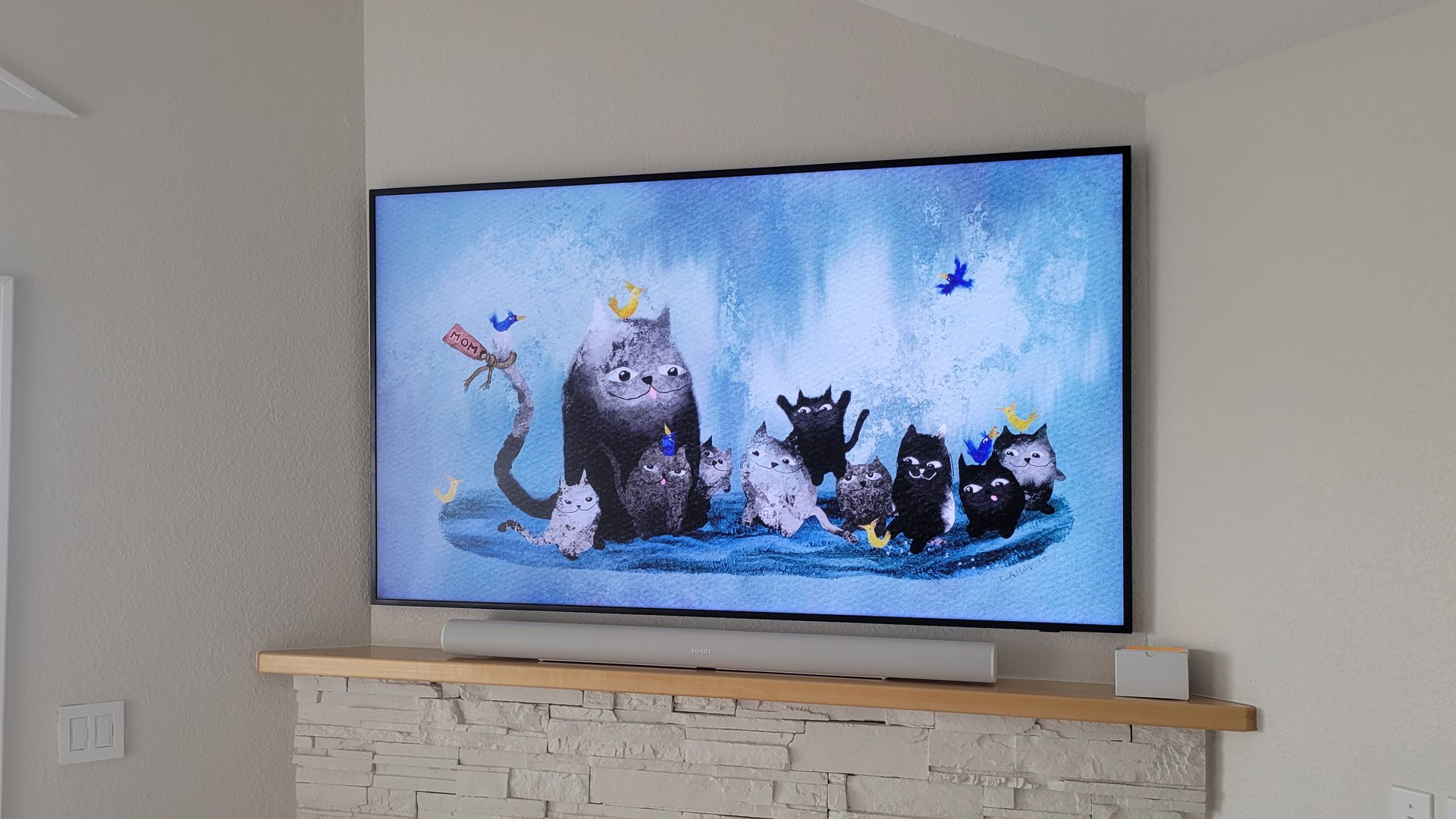 A samsung frame TV mounted above a fireplace with a sonos soundbar.