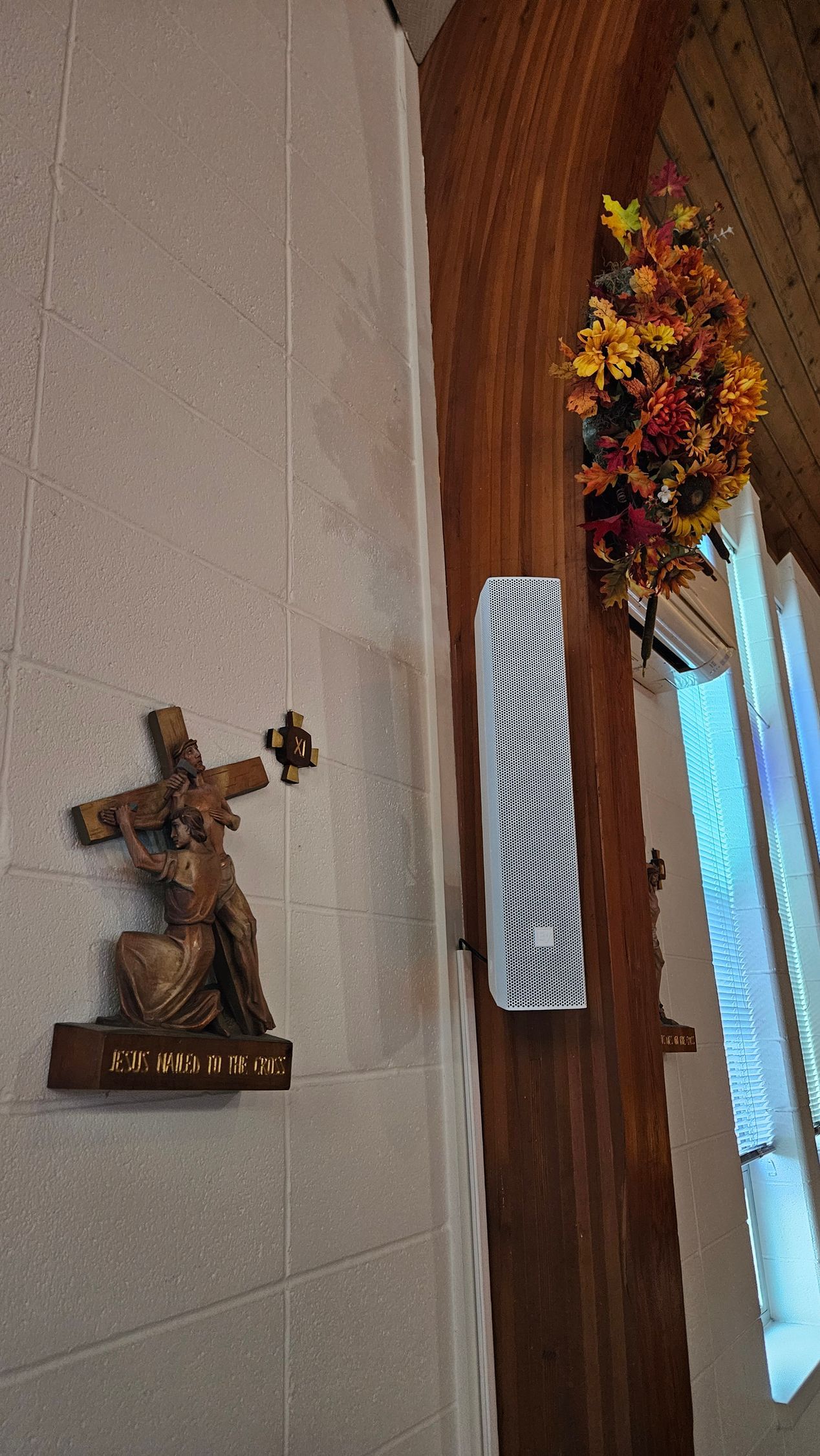 Bronze sculpture of Jesus carrying the cross, next to a LRC audio speaker for house of worship audio.
