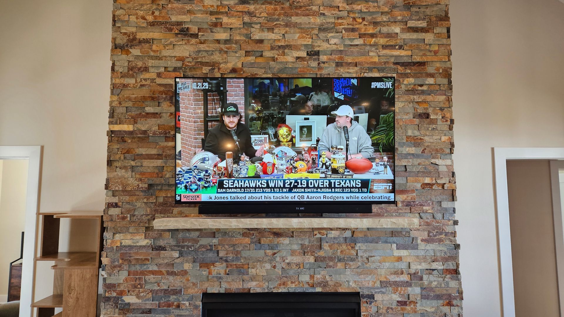 TV and soundbar custom mounted on a stone fireplace.