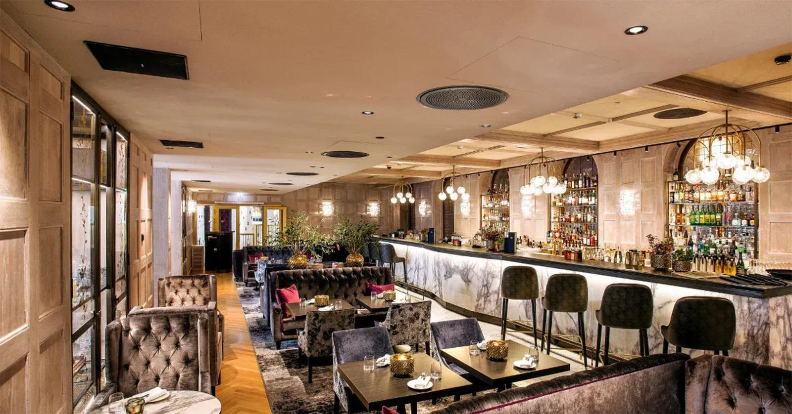 Interior view of a bar with seating, and a speaker system installed in the ceiling.