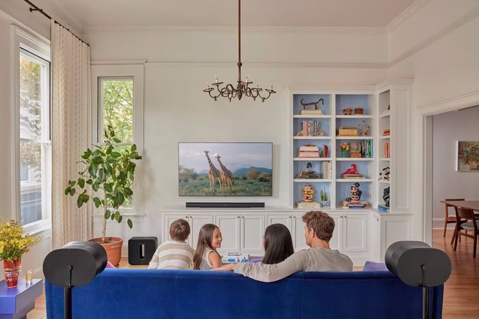 Family watching TV on a blue couch with a sonos home theater system