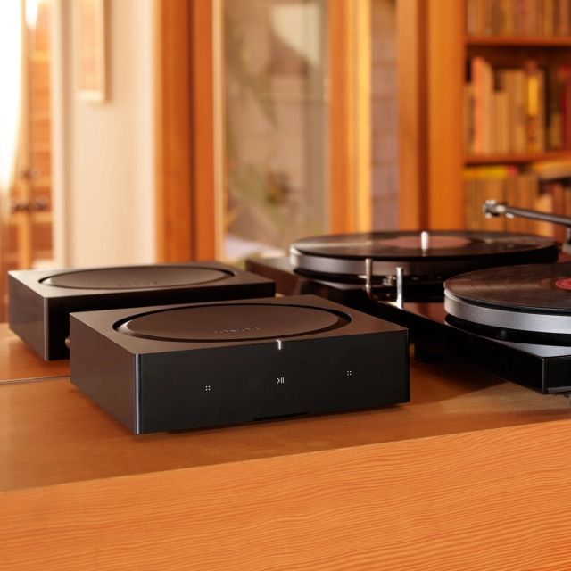 A sonos amp with turntables and a bookcase in the background.