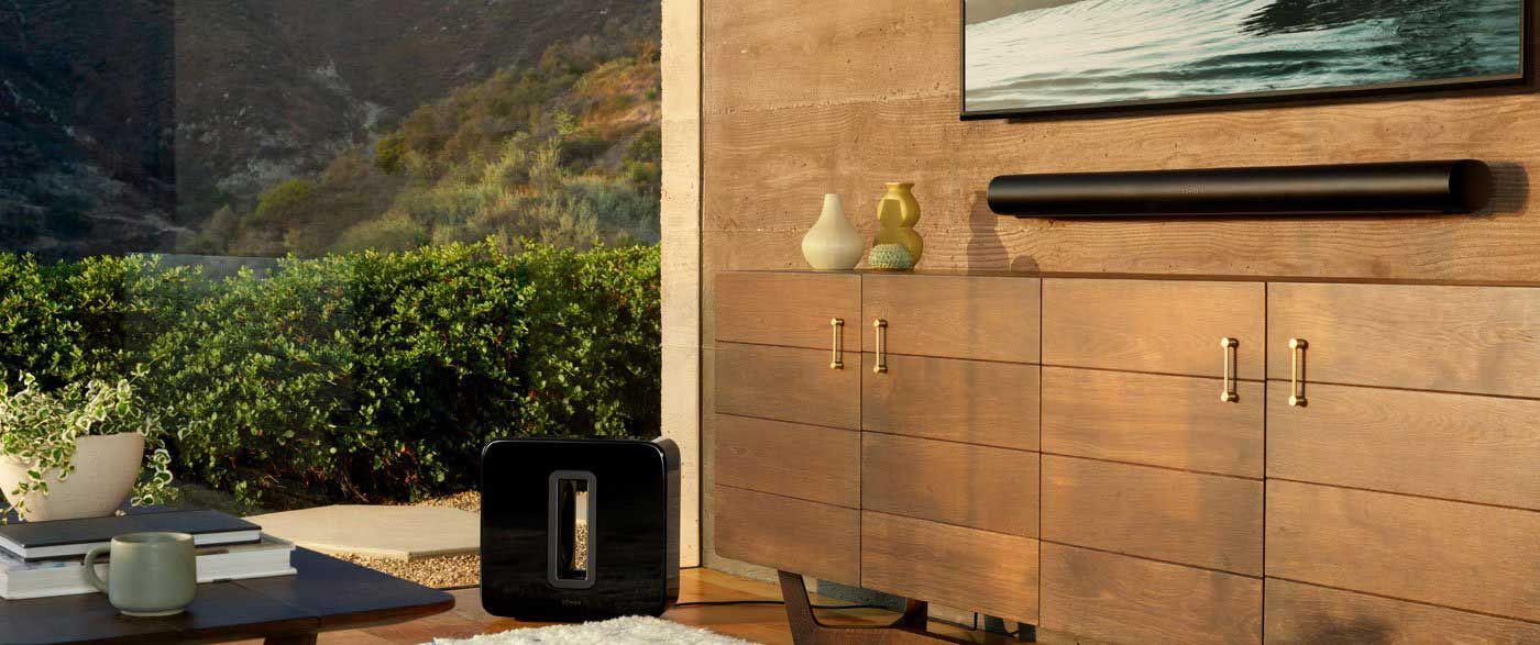 Modern living room with a sonos arc soundbar system, cabinetry, and a view of nature through the window.