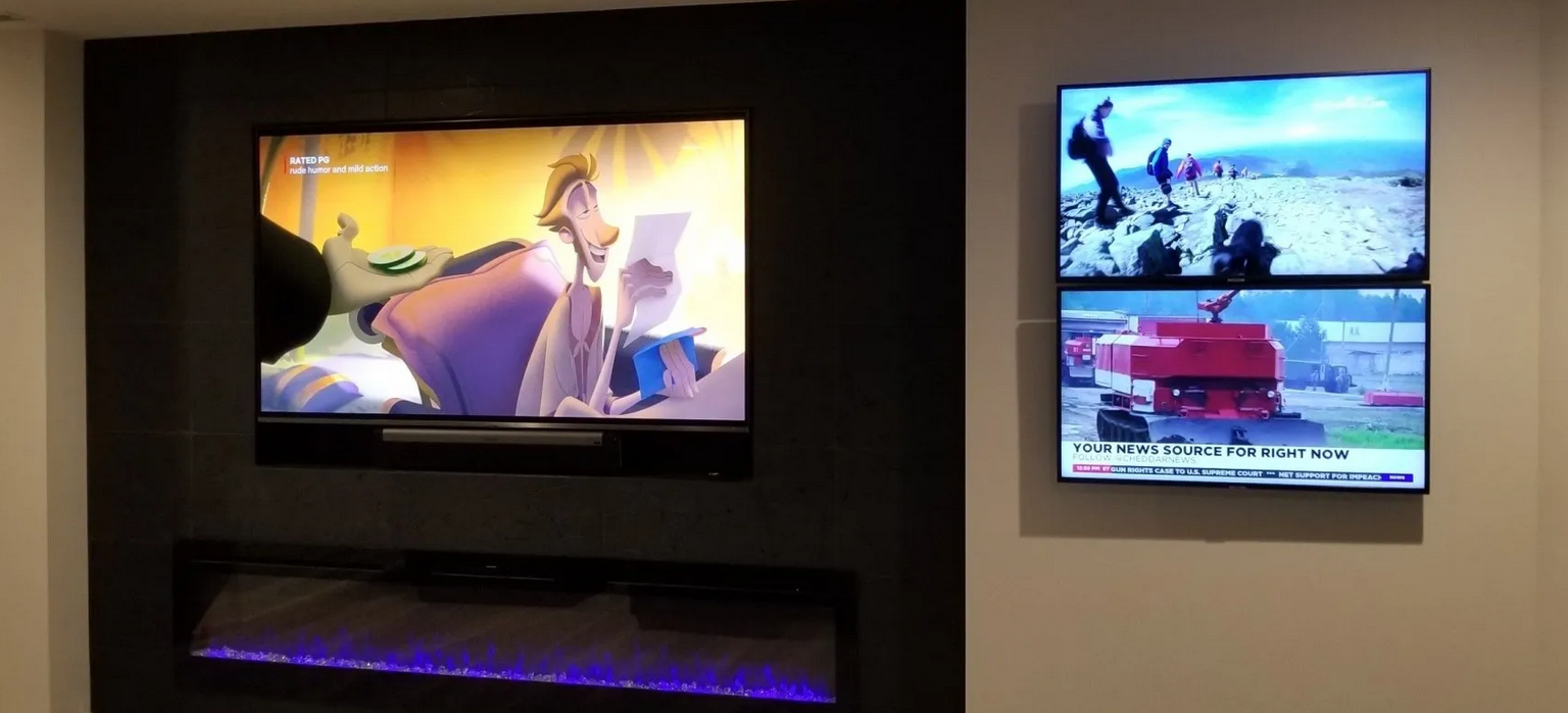 Two TVs on a wall, one showing animation, the other news. A purple light strip is below the animation TV.