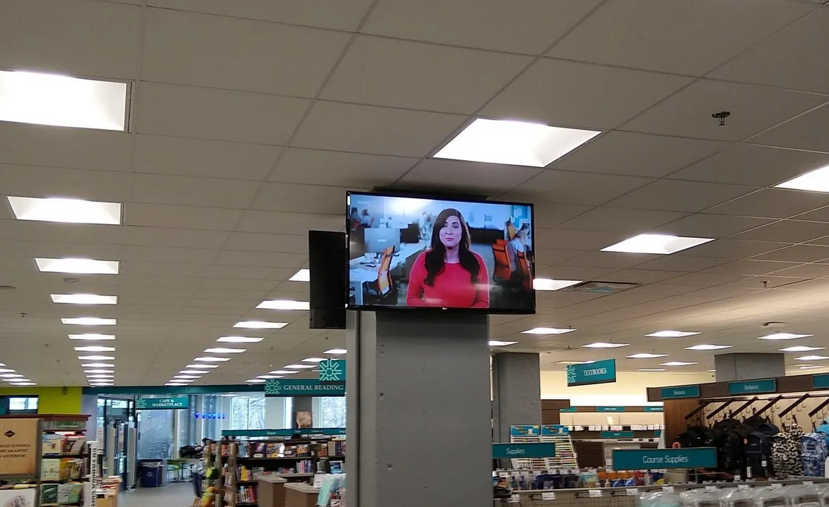 Two TVs custom mounted on a pillar inside a store with a video system installed. 