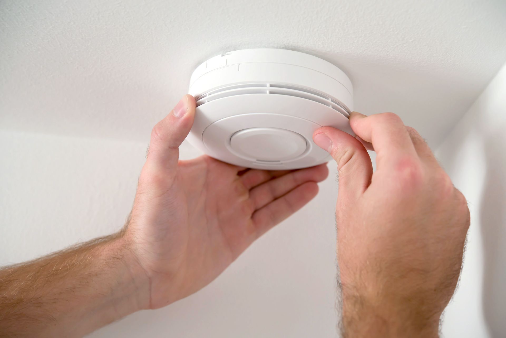 A handyman installing a smoke detector on the ceiling.