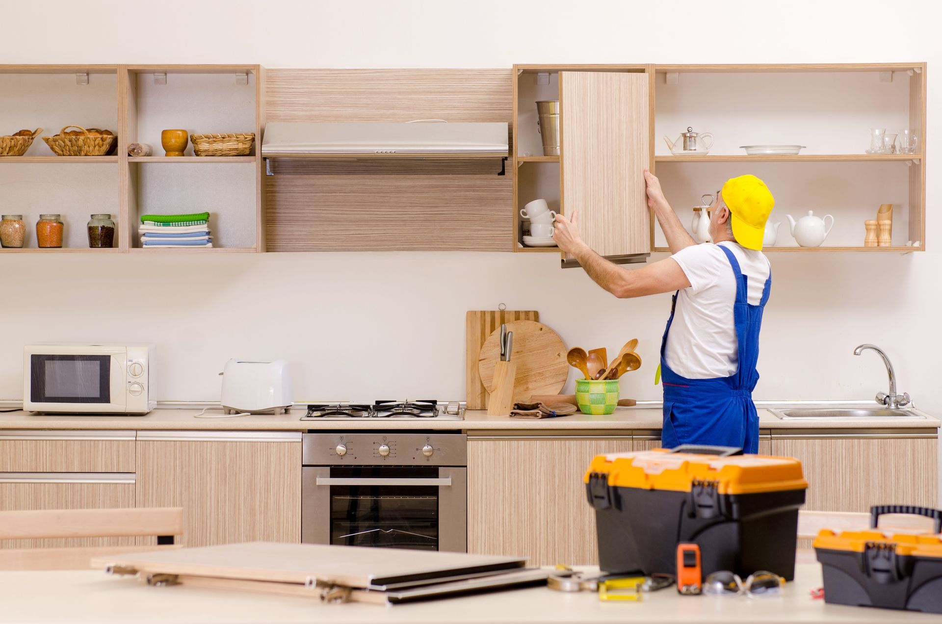 An experienced handyman carefully installs a sturdy wooden shelf in a well-organized kitchen.