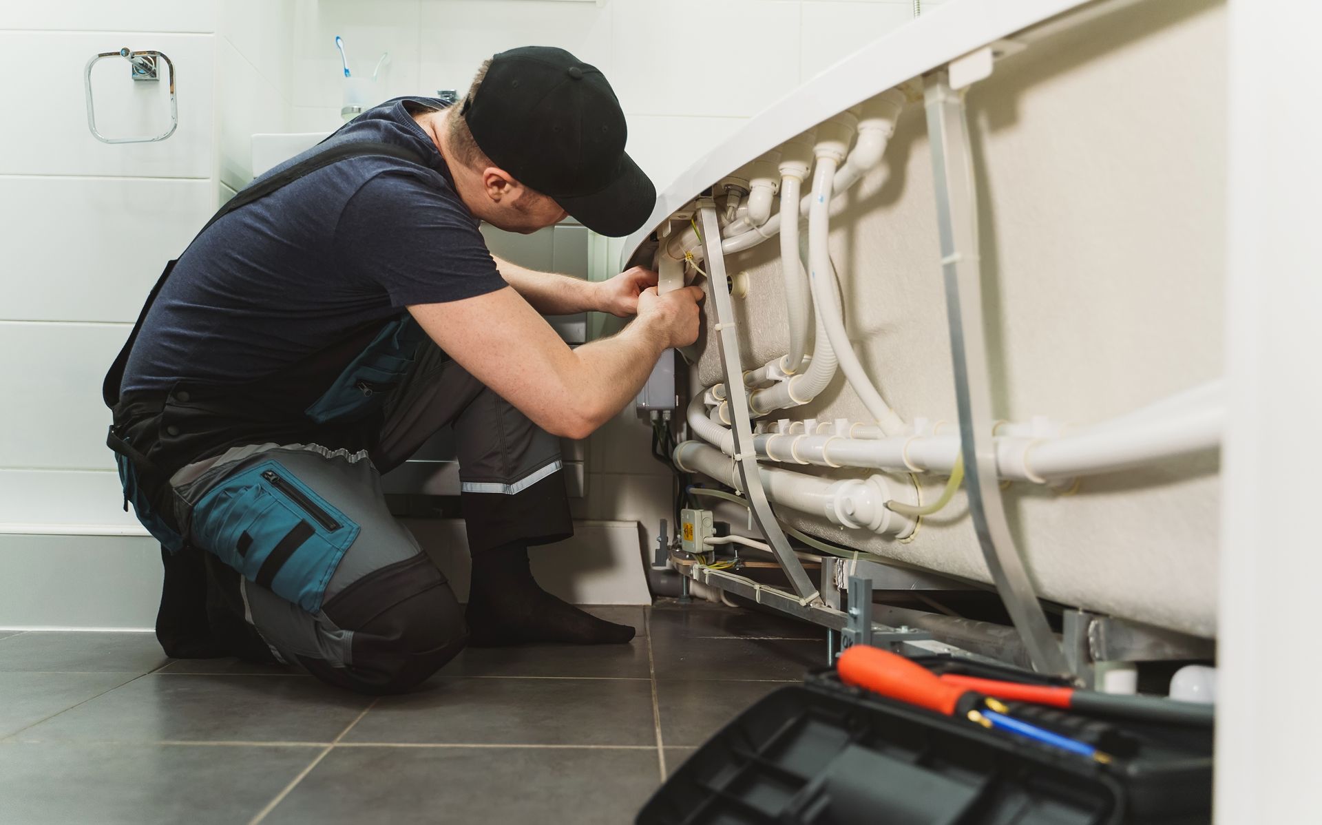 A skilled man installs a pipe system for a hydromassage bathtub.