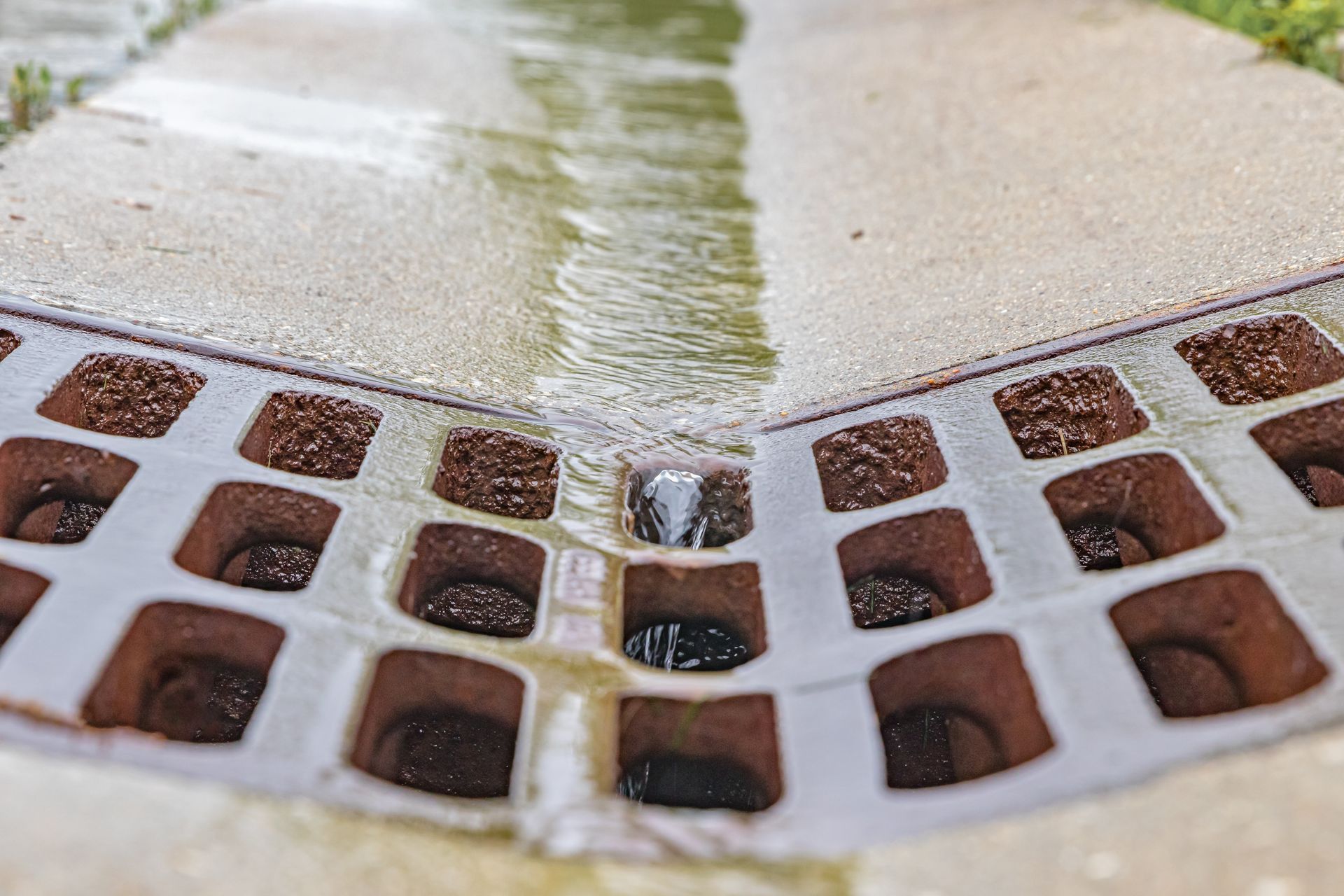 Closeup of rainwater cascading down a street gutter, seamlessly flowing towards a storm sewer system drainage grate.