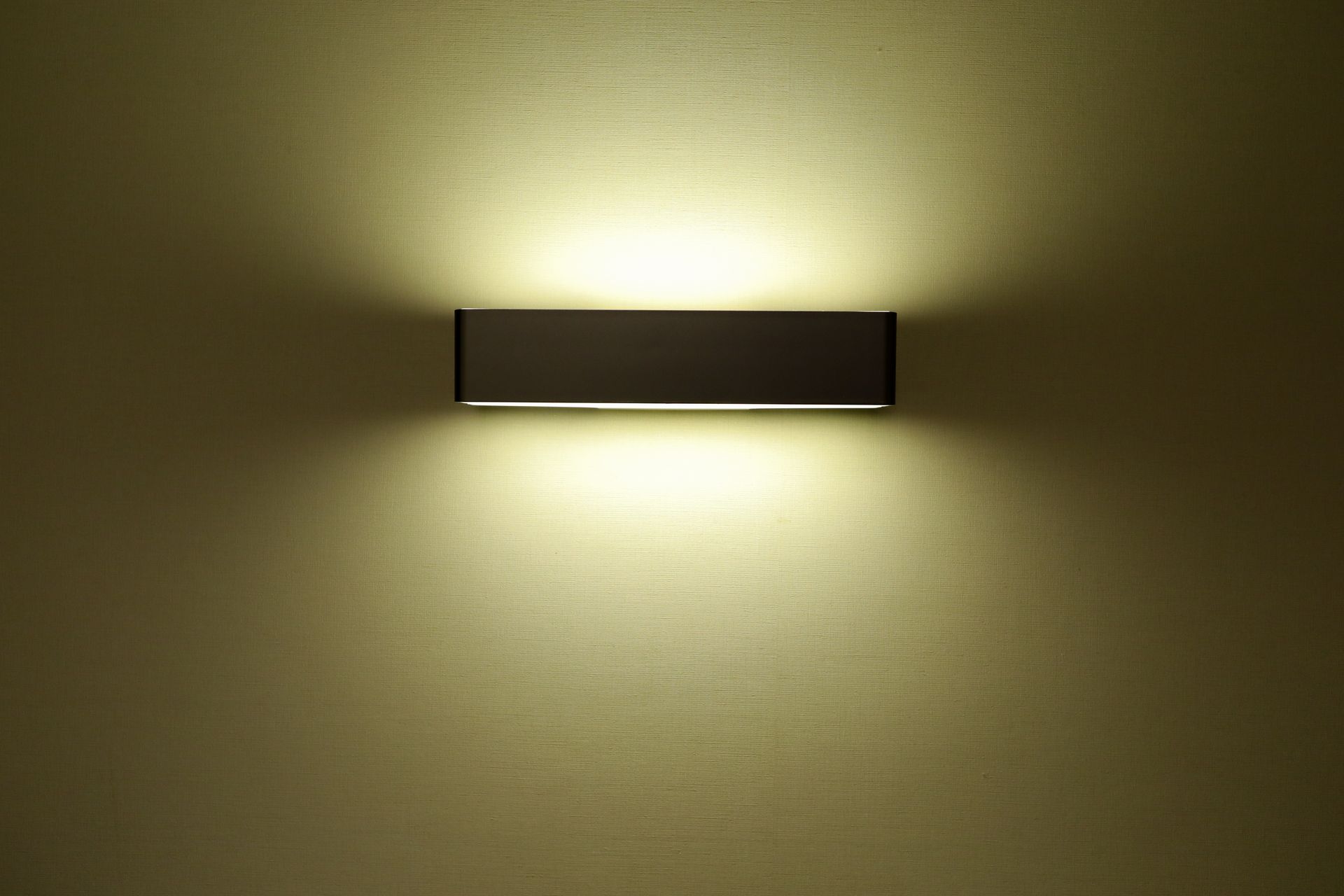 An illuminated light bulb affixed to a wall, casting a warm glow with its soft yellow light.