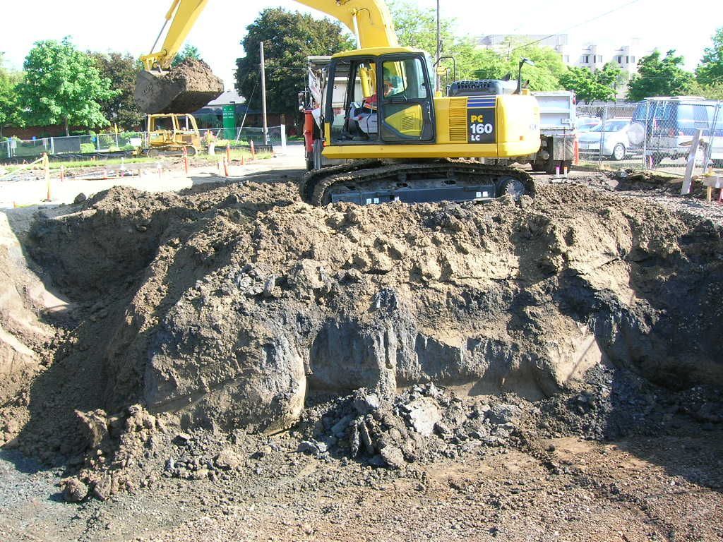 A Yellow Excavator On A Dirt Mound — Eugene, OR — Emerald Excavating