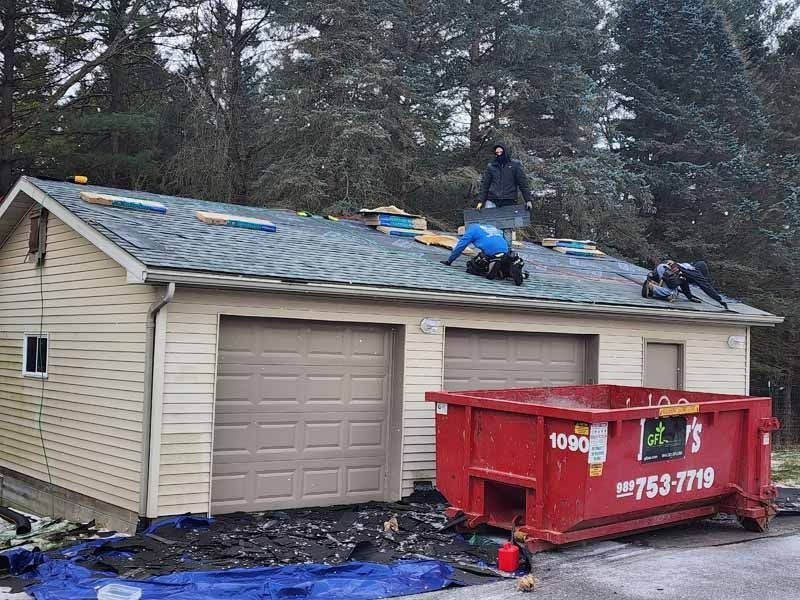 A couple of men are working on the roof of a garage.
