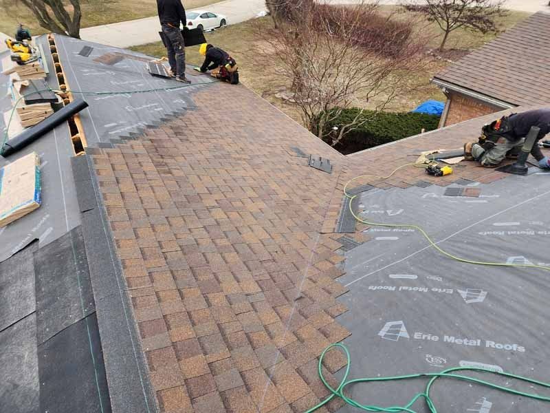 A group of men are working on a roof of a house.