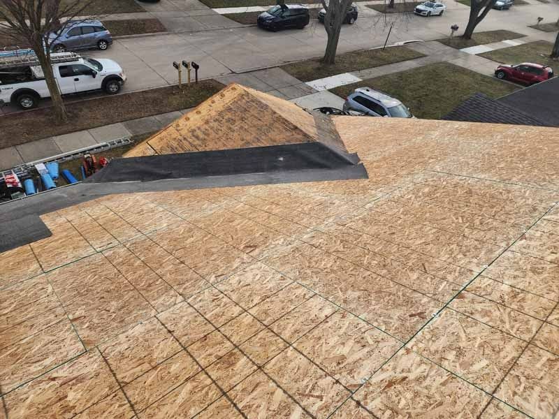 An aerial view of a roof under construction in a residential neighborhood.