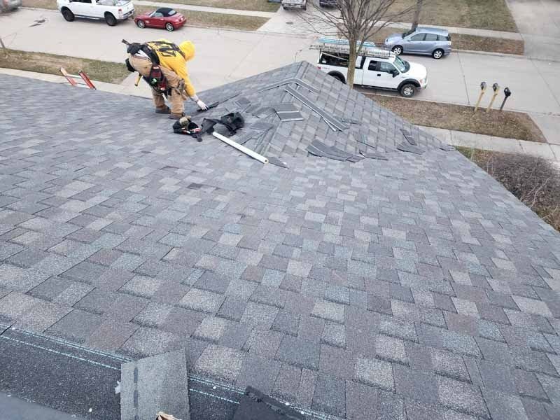 A man is working on the roof of a house.