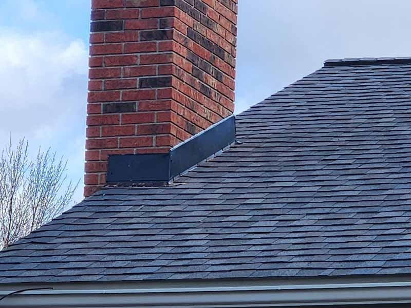 A brick chimney is on the roof of a house.