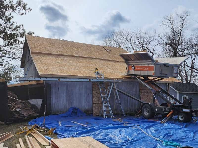 A man is working on the roof of a barn.