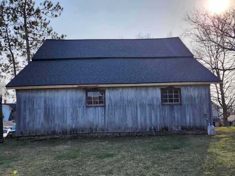 A barn with a blue roof and a few windows
