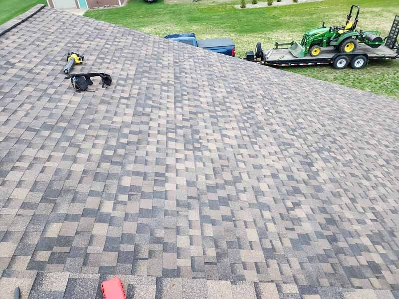 A tractor is on a trailer on the roof of a house.