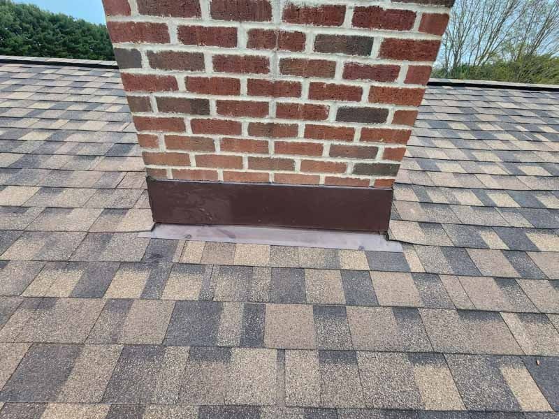 A brick chimney is sitting on top of a roof.