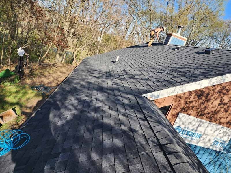 A man is working on the roof of a house.
