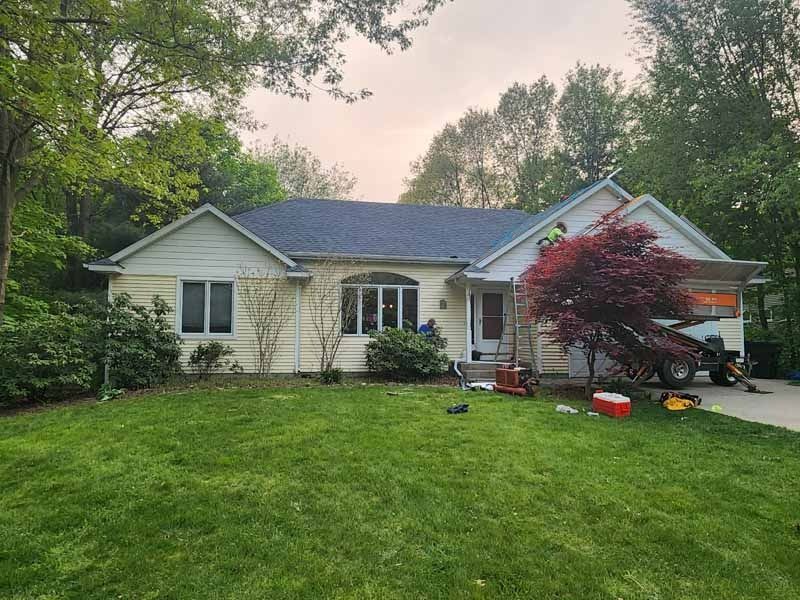 A white house with a blue roof and a large lawn in front of it.