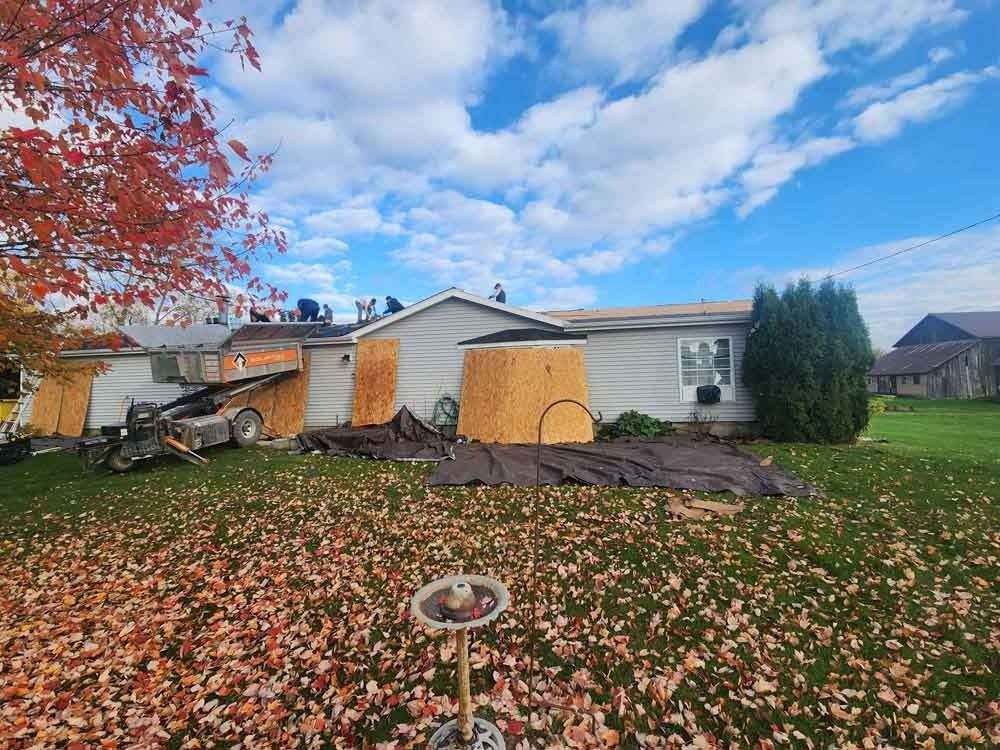 A house with a lot of leaves on the ground in front of it.