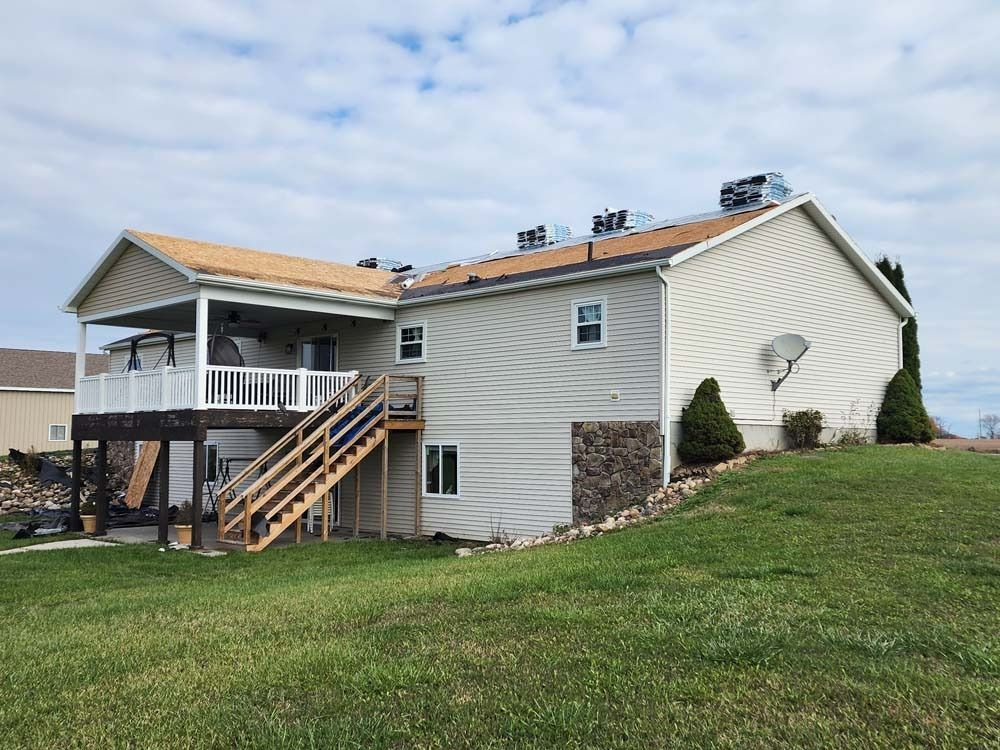 The back of a house with a large deck and stairs leading up to it.