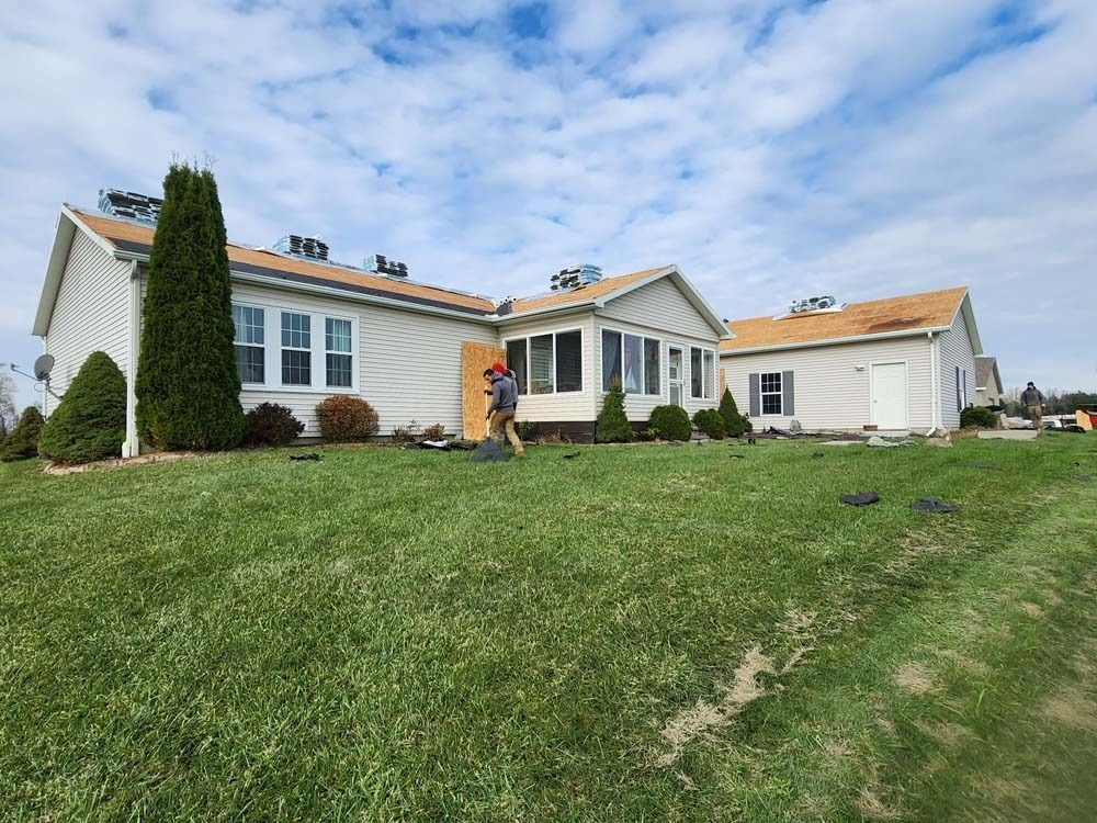 A man is walking in front of a white house with a red roof.