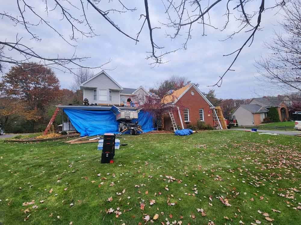 A house with a blue tarp on the roof is being remodeled.