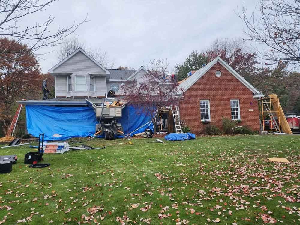 A brick house is being remodeled with a roof being installed.