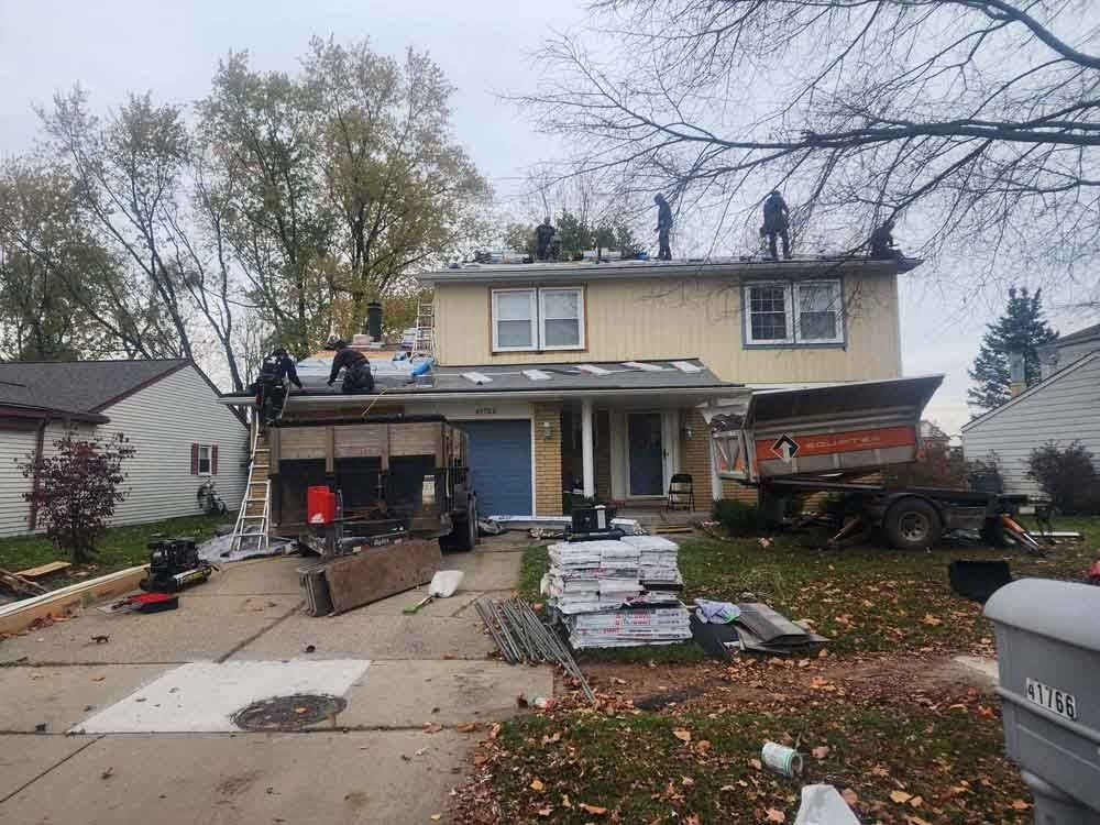 A group of people are working on the roof of a house.