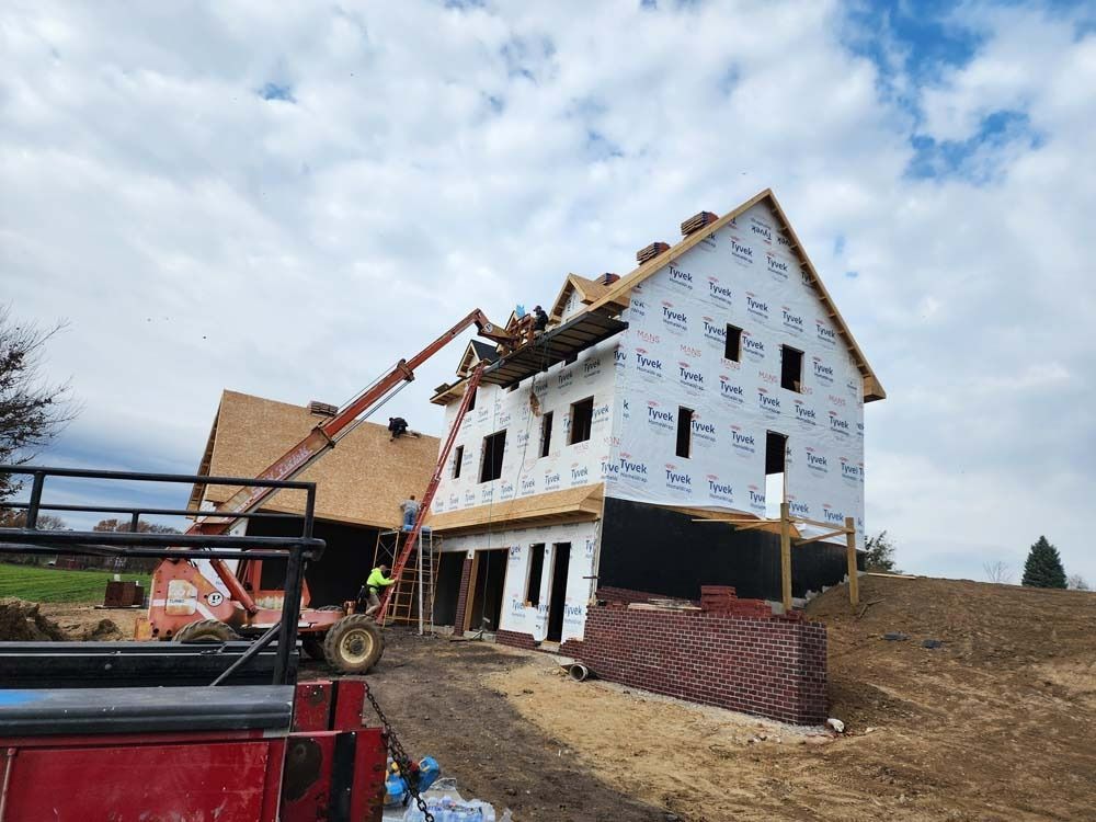 A red truck is parked in front of a house under construction.