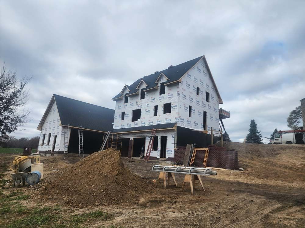 A large house is being built in a dirt field.