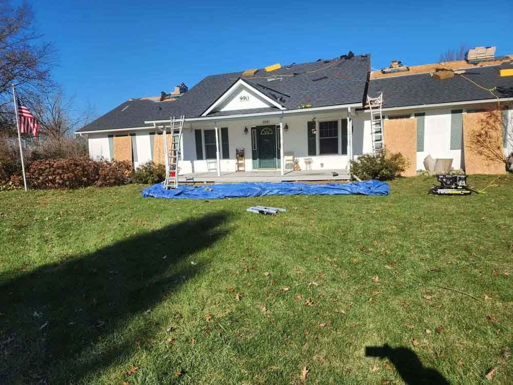 A house with a roof that is being installed is sitting on top of a lush green lawn.
