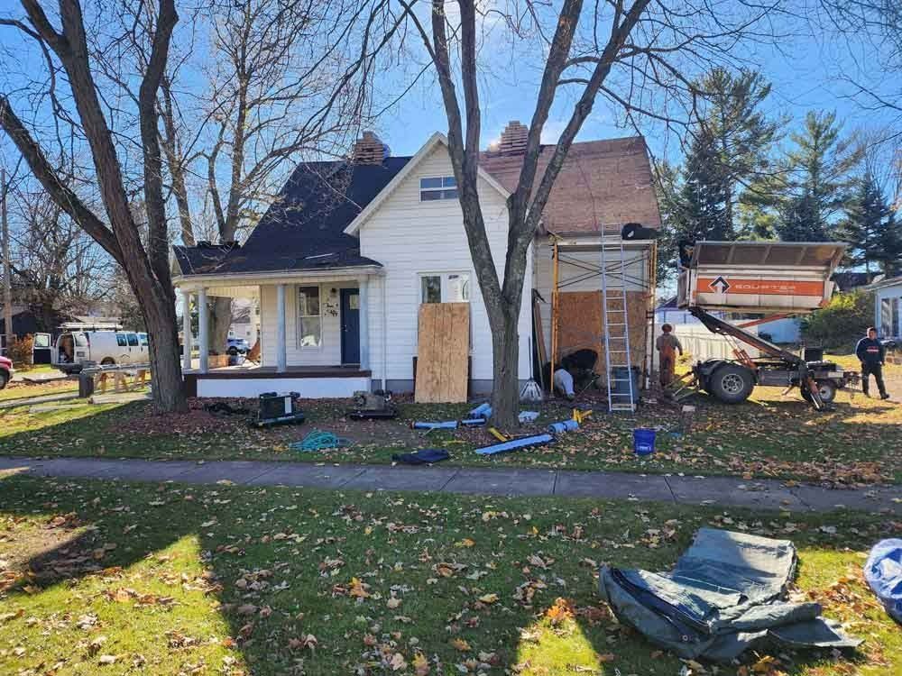 A white house with a black roof is being remodeled.
