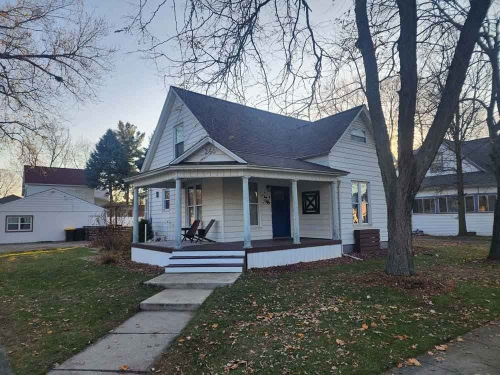 A white house with a porch and trees in front of it.