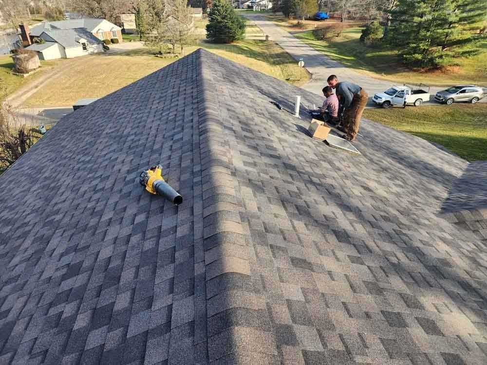 Two men are working on the roof of a house.