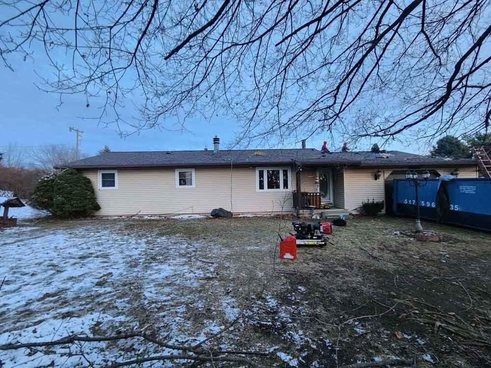 A house with a roof that is being installed in the snow.