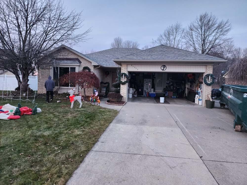A house decorated for christmas with a green truck parked in front of it.