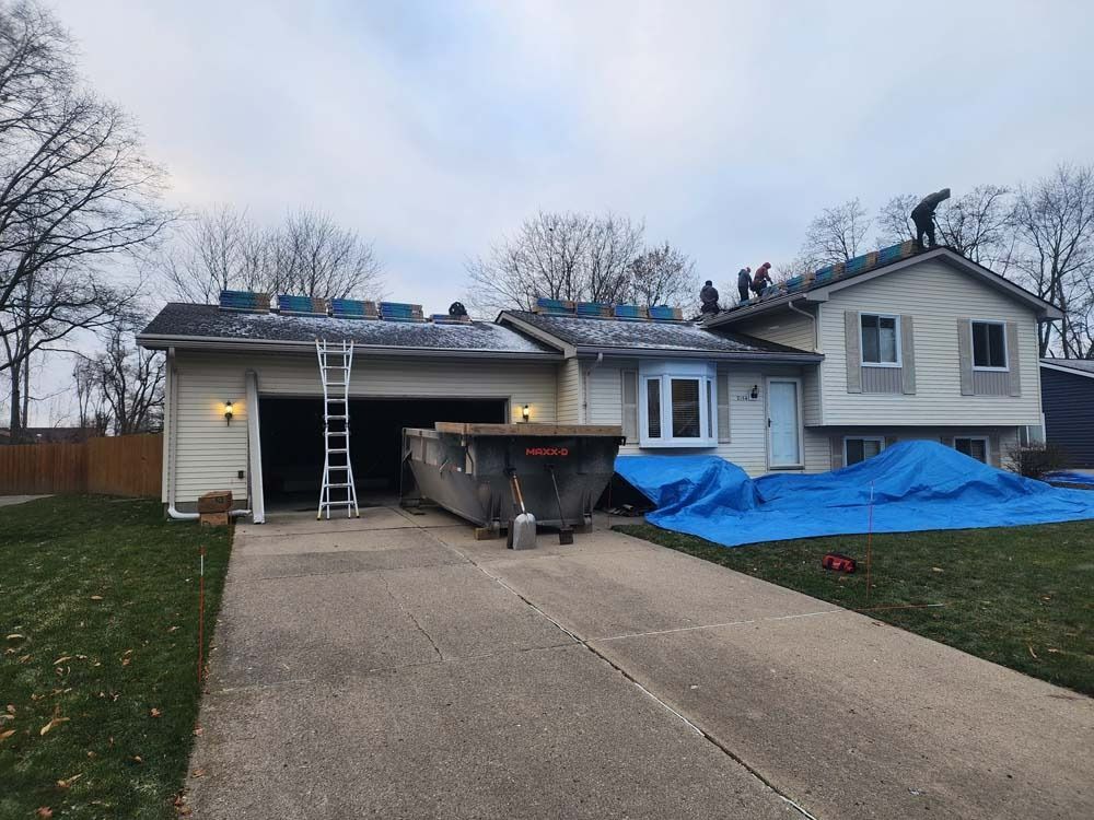 A house with a ladder and a dumpster in front of it.