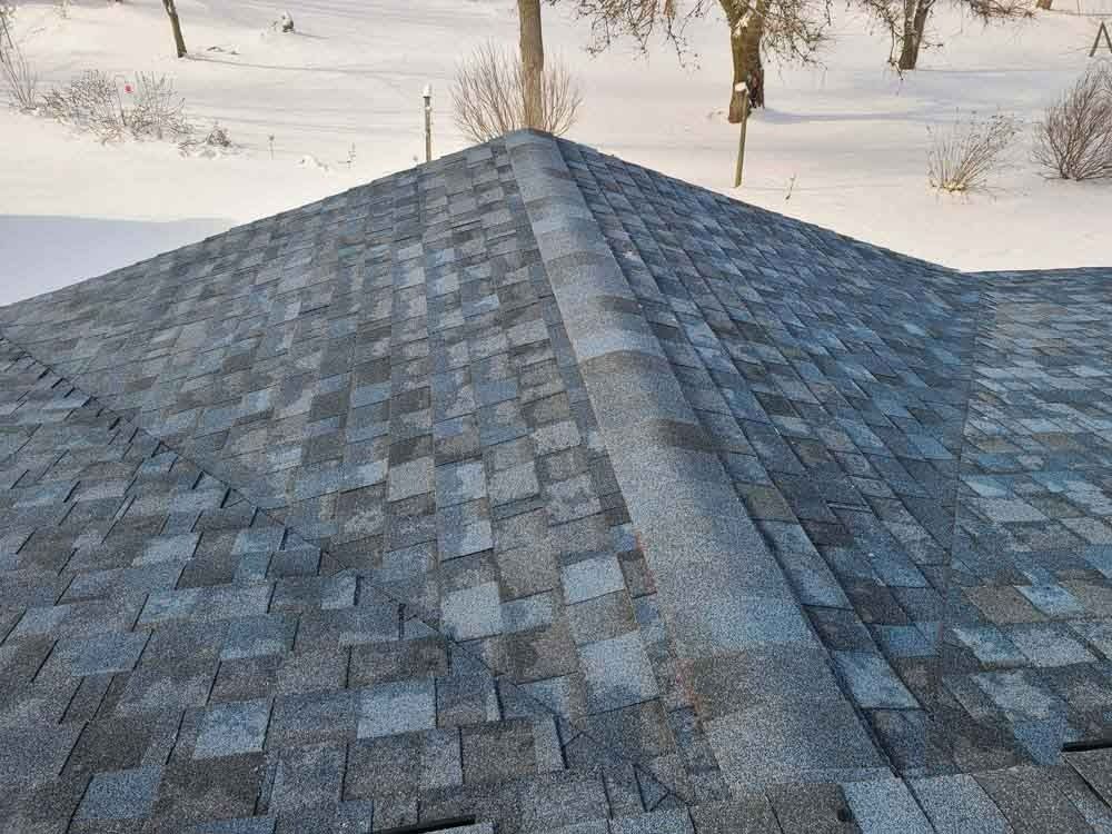 A close up of a roof with snow on the ground in the background.