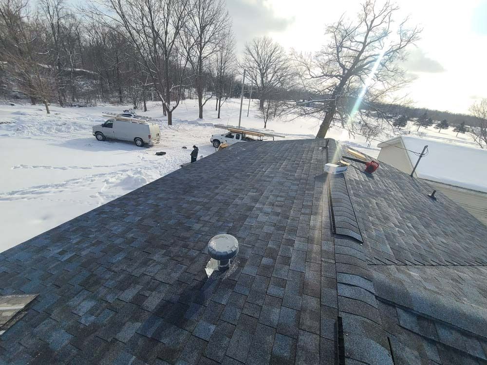 A van is parked on the roof of a house in the snow.
