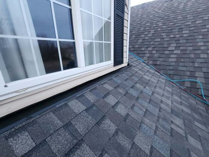 The roof of a house with a window and a hose attached to it.