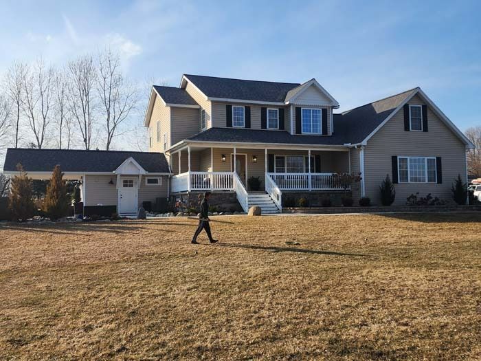 A man is walking in front of a large house.
